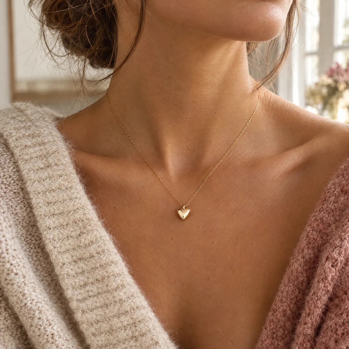 Goldfarbene Herzkette an einem Hals, weicher Pullover